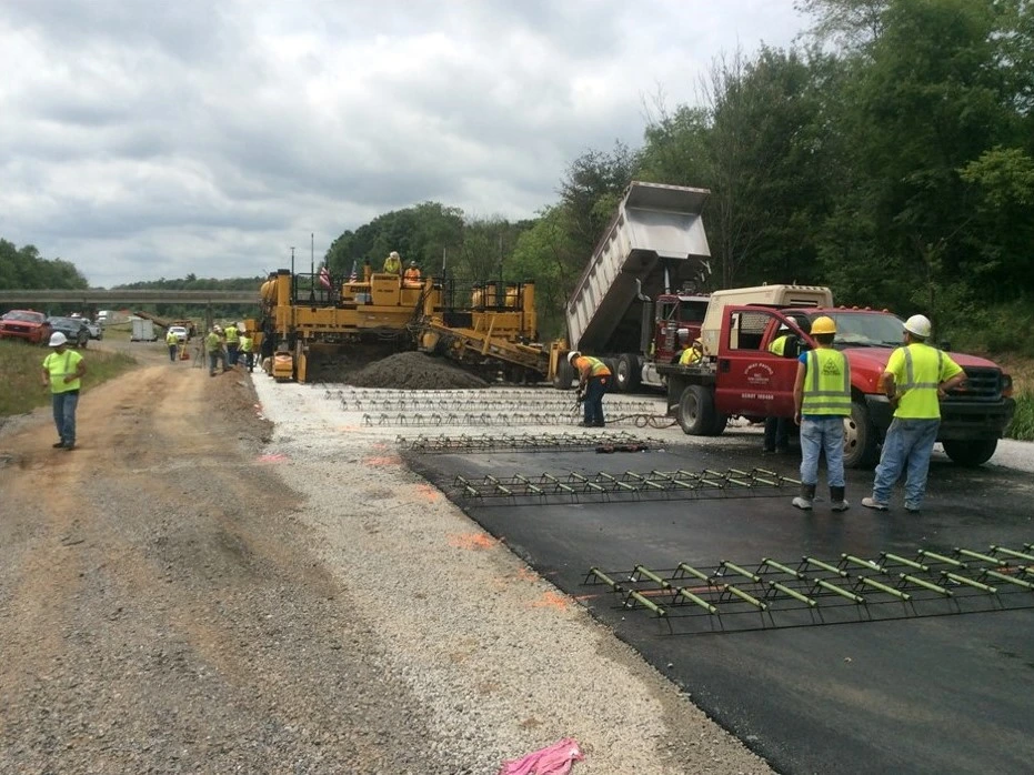 An image of construction workers applying a pavement overlay to a roadway.